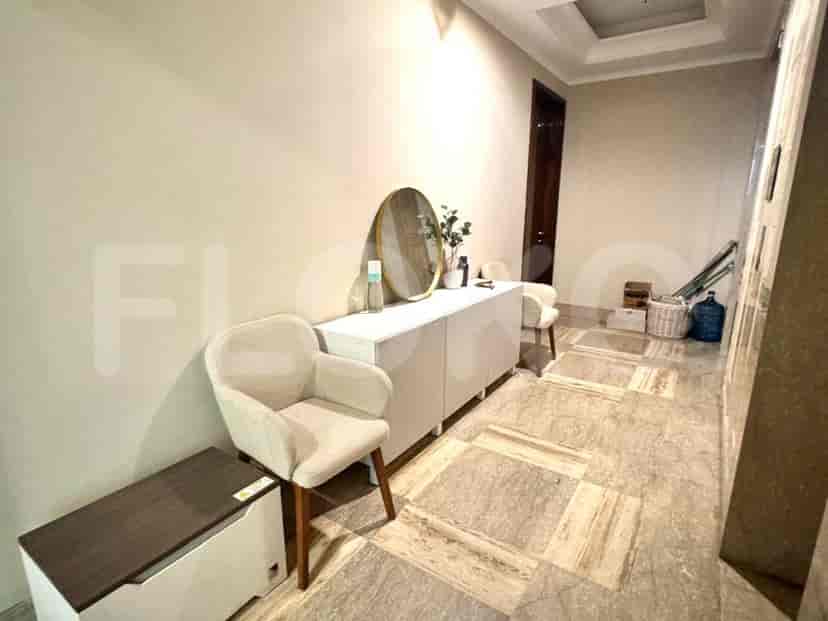 A hallway with a console table, two chairs, and a decorative mirror.