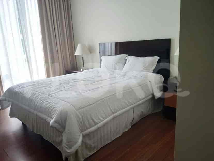 A bedroom with a bed, a bedside table, and a large window with curtains.