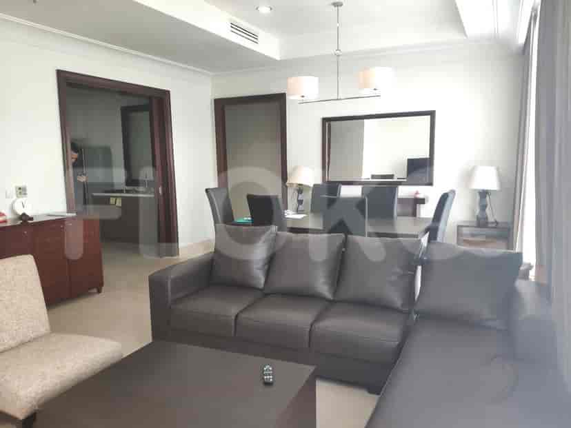 A living room with an L-shaped grey sofa, dining table, and a doorway to the kitchen.