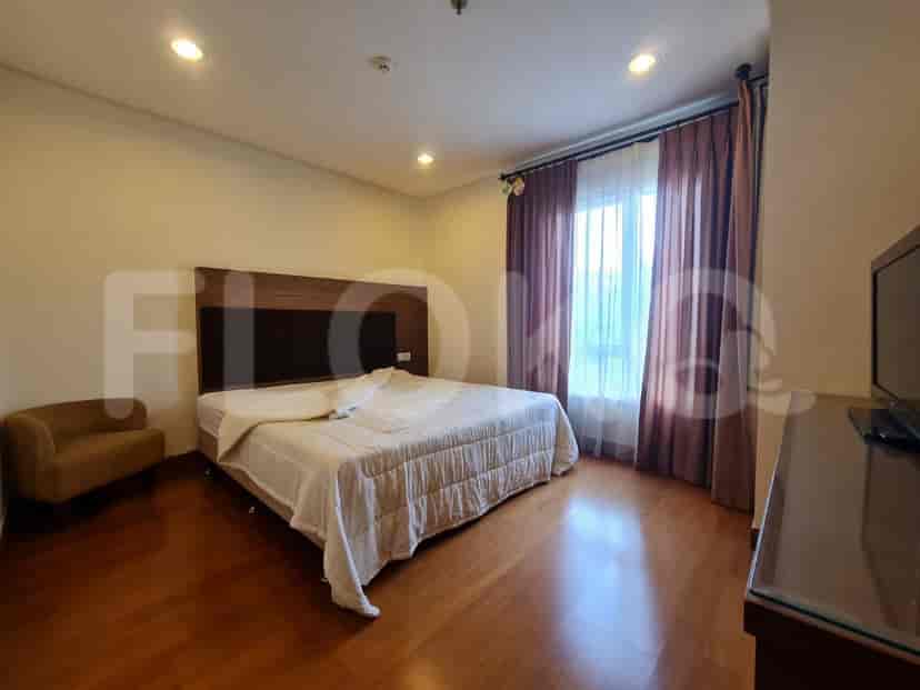 A spacious bedroom with a king-size bed, wooden flooring, and large window.