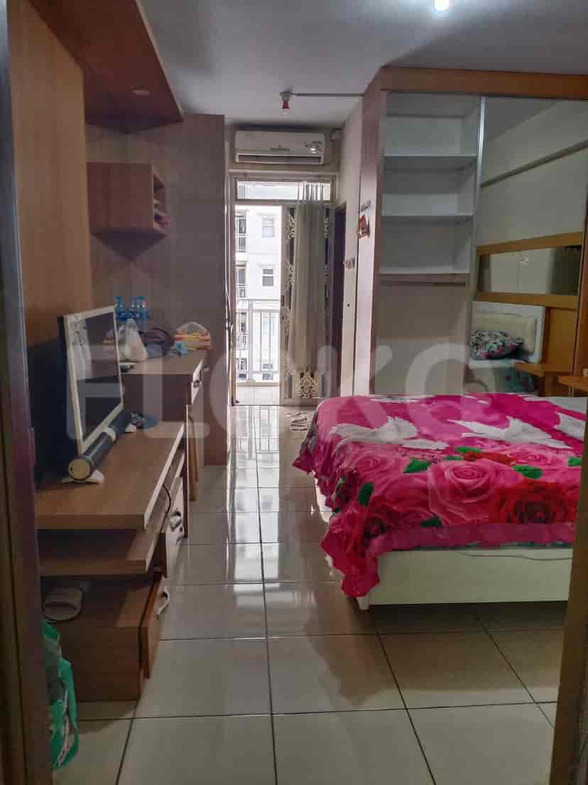 Kamar tidur ringkas yang menampilkan tempat tidur dengan selimut bermotif bunga, lemari pakaian dengan pintu cermin, dan meja.