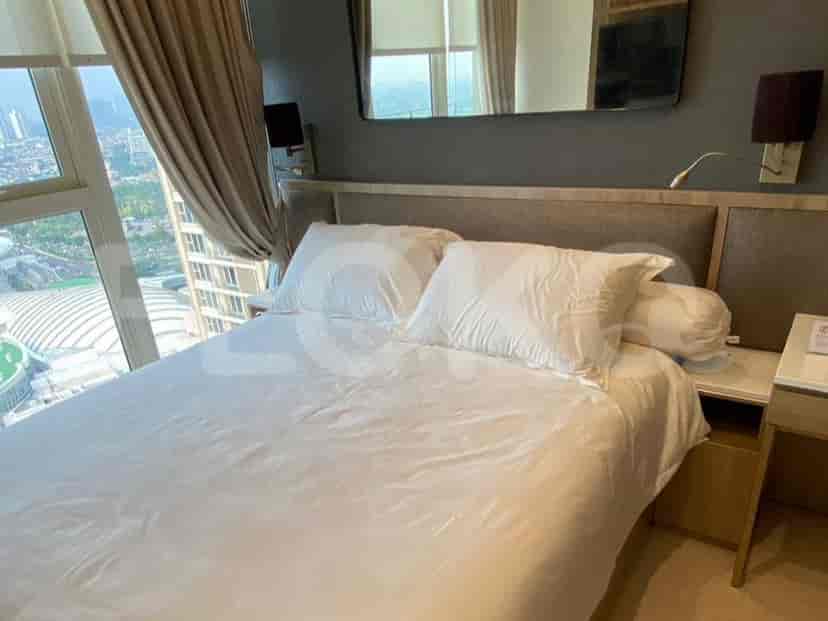 A modern bedroom featuring a king-sized bed, mirror, and city view.
