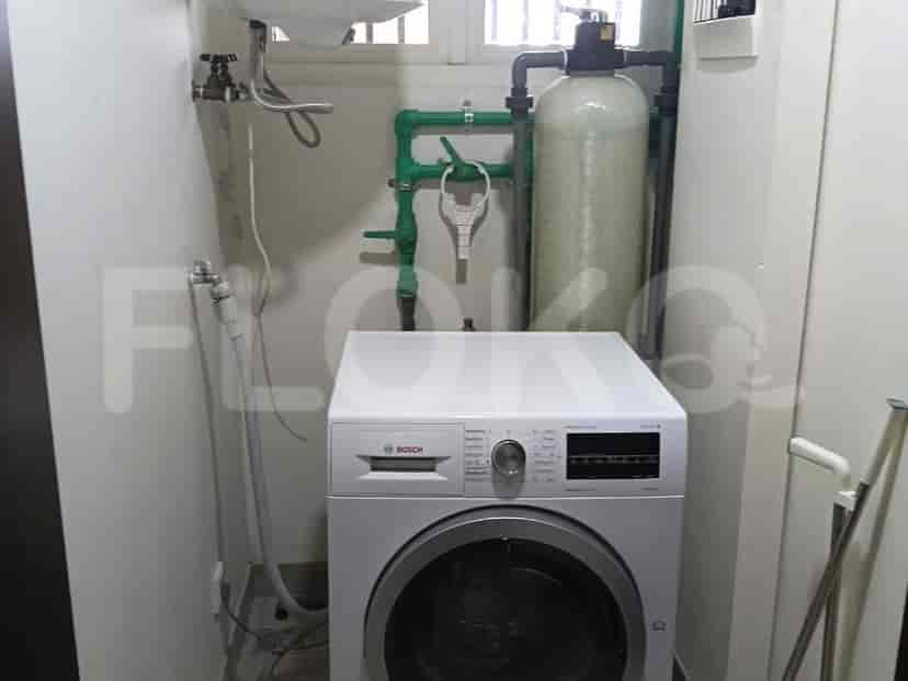 A small laundry room with a washing machine and utility sink.