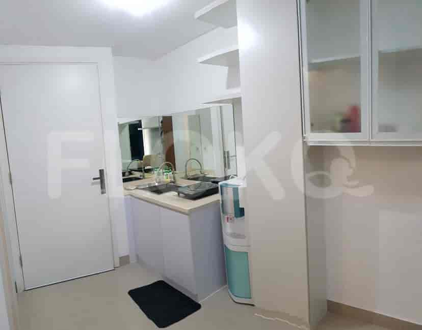 A small, modern kitchenette with a sink, cabinetry, and a water dispenser.