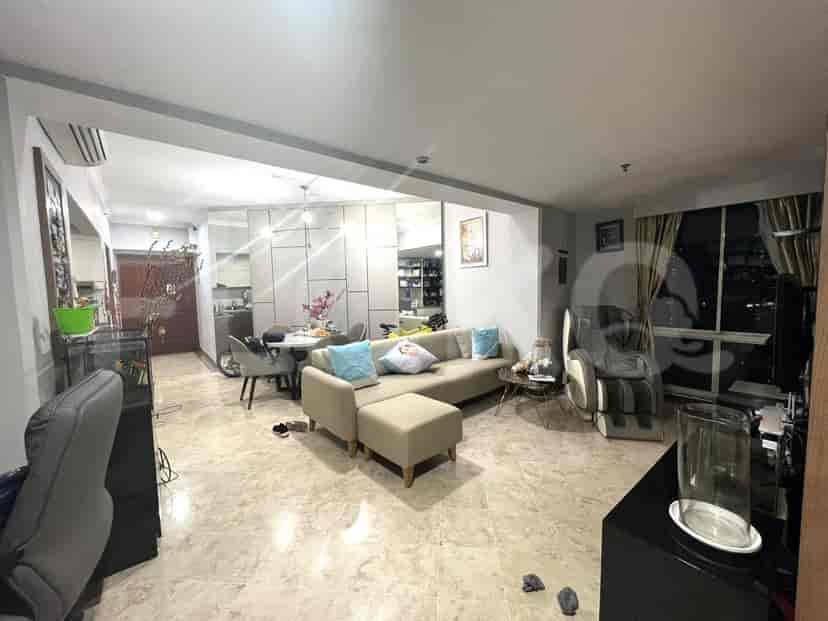 A spacious living room with a beige sectional sofa, a dining area, and an open kitchen.