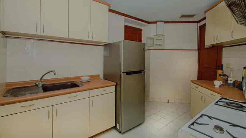 Dapur dengan lemari, peralatan, dan lemari es.