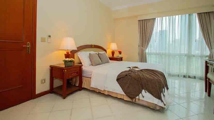 Kamar tidur yang nyaman dengan tempat tidur, meja samping tempat tidur, dan gorden.