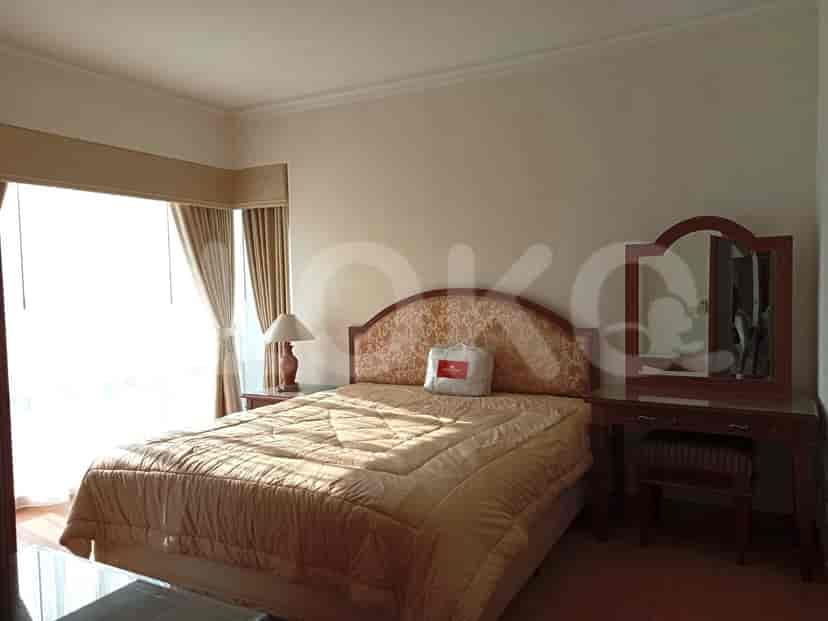 Well-lit bedroom with a double bed, dressing table, and curtains.