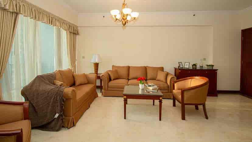 Ruang tamu bernuansa hangat yang menampilkan sofa, kursi, dan meja kopi.