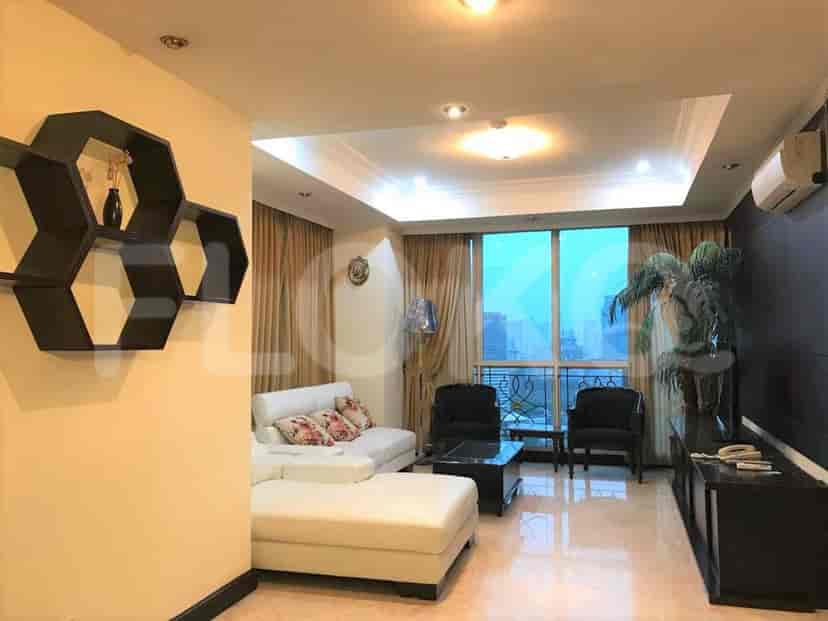 Ruang tamu dengan sofa putih, meja samping, dan pemandangan kota.