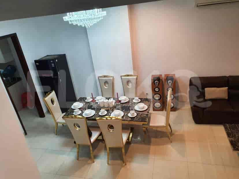 An elegant dining area with a marble dining table, gold chairs, and speakers.