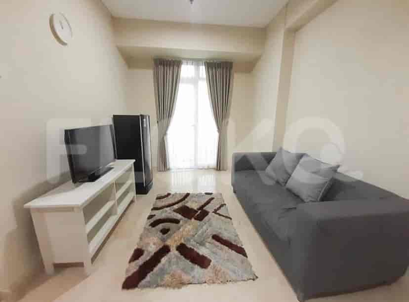 A well-lit living room featuring a grey sofa, TV, and a patterned rug.