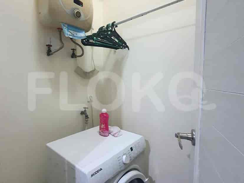 A laundry room with a washing machine and drying rack.