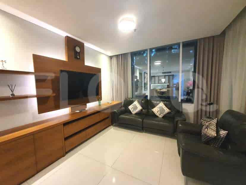 A living room with a wooden entertainment center, a black leather sofa, and large windows with curtains.
