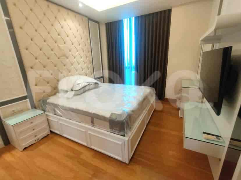 A bedroom with a queen-sized bed, bedside table, and a window with curtains.
