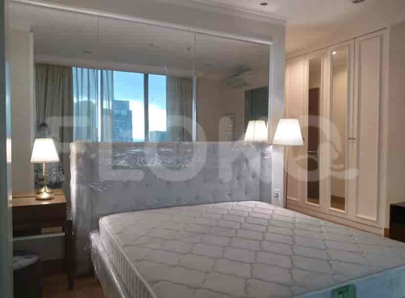 A bedroom featuring a large bed, a wall-mounted mirror, and a wardrobe.