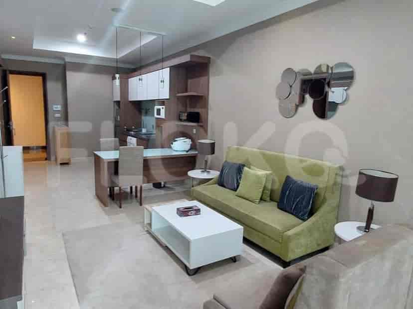 A modern living space with a combined kitchen and dining area. Features include a green sofa, a white coffee table, and a dining table with chairs.