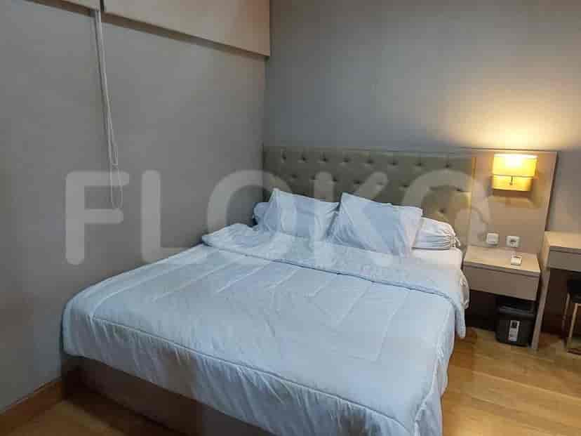 A minimalist bedroom featuring a double bed with a white duvet and a bedside table.