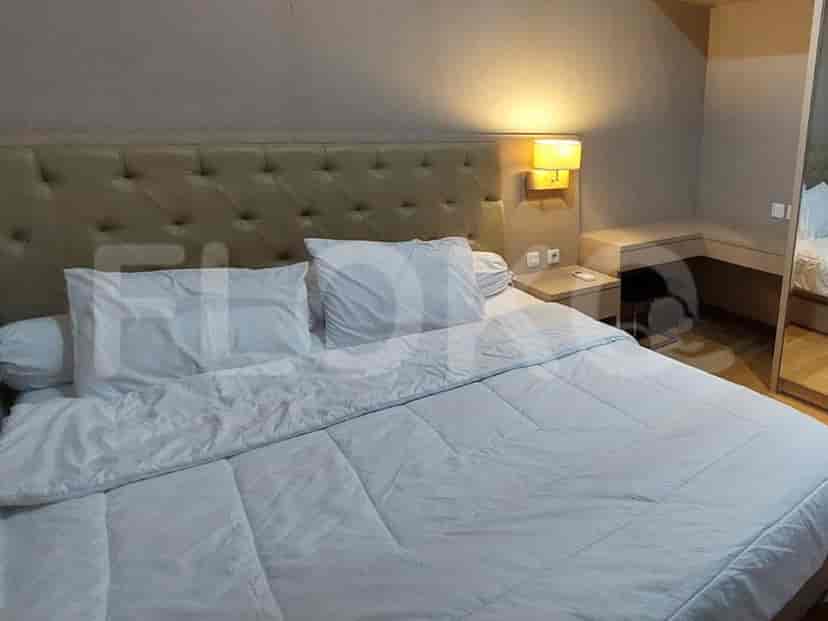 A bedroom with a large bed, a bedside table and a wall-mounted lamp.