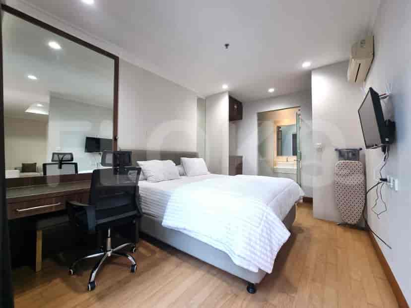 Modern bedroom featuring a bed, desk, and large mirror.