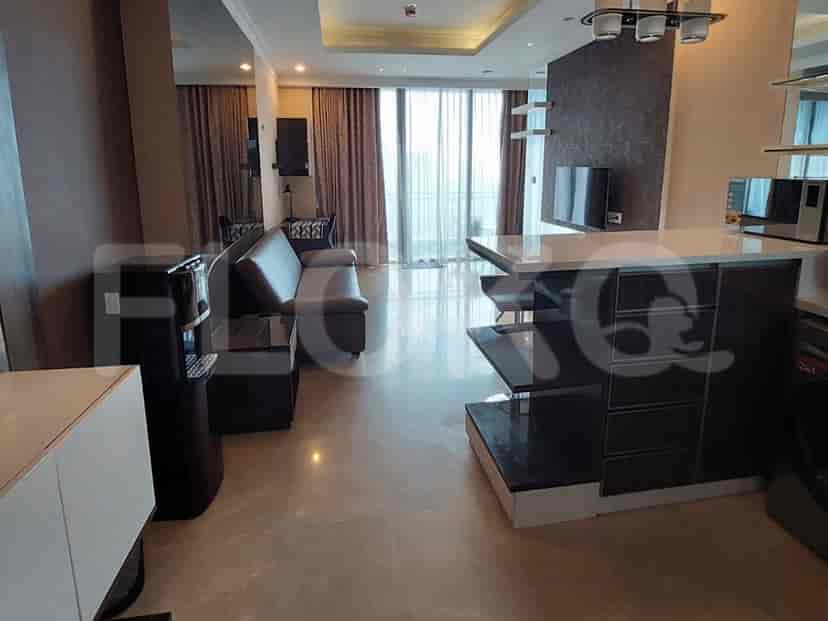 Spacious living room with an L-shaped grey sofa, wall-mounted TV, and large windows.