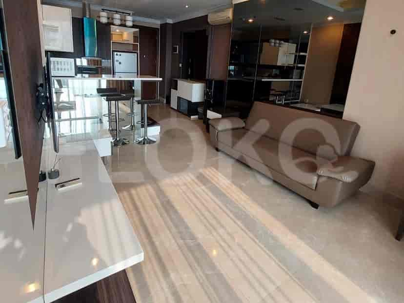 Living room with a brown leather sofa, a kitchen island, and a smart TV.