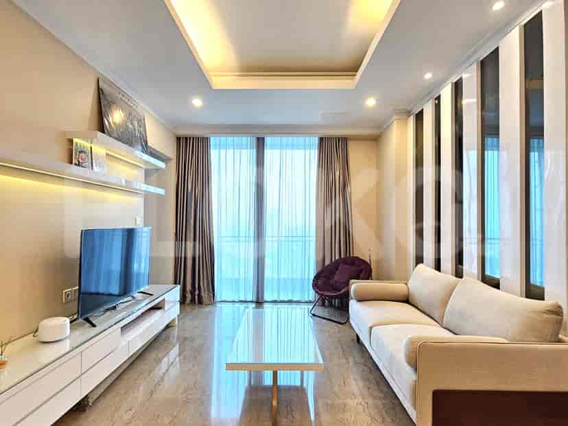 Modern living room with a sofa, a glass table, and a TV against a wall.