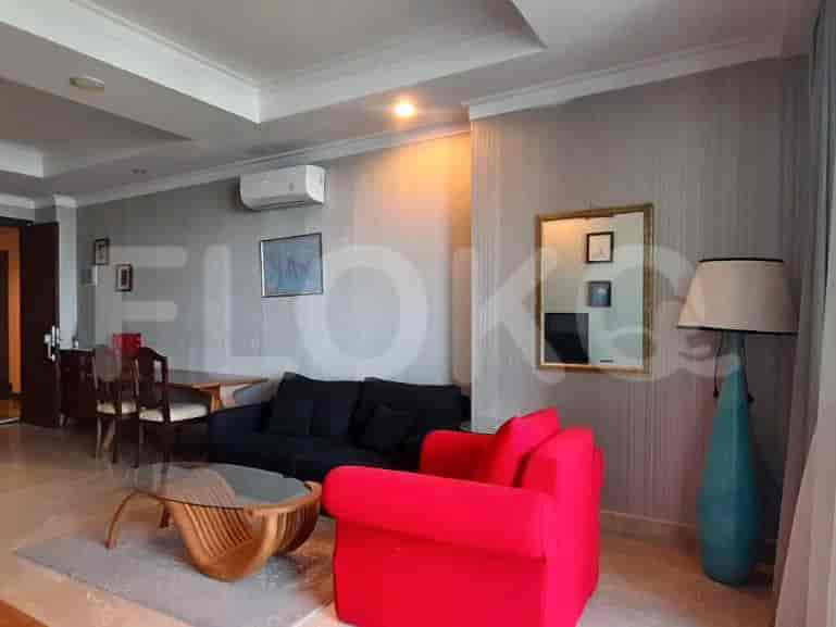 Spacious living room with a black sofa, red armchair, and glass table.