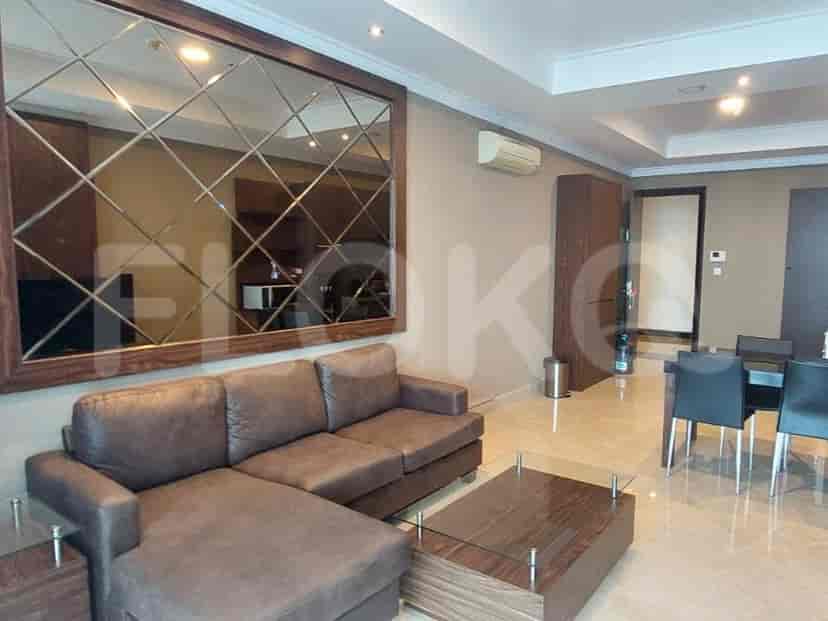 Living area with a brown L-shaped sofa, mirrored wall decor, and a dining area.