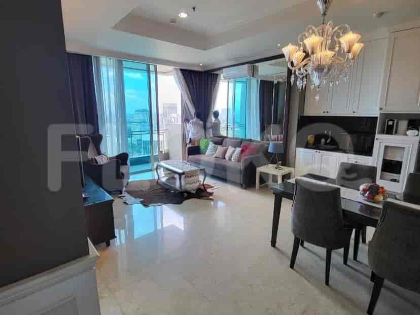A living room with a grey sofa, coffee table, and large windows.