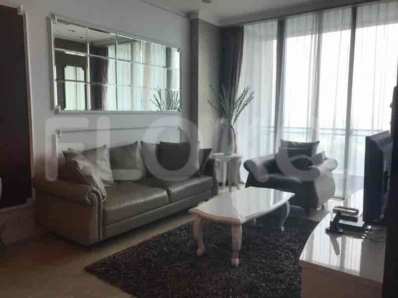 Modern living room with a sofa, TV, and large windows.