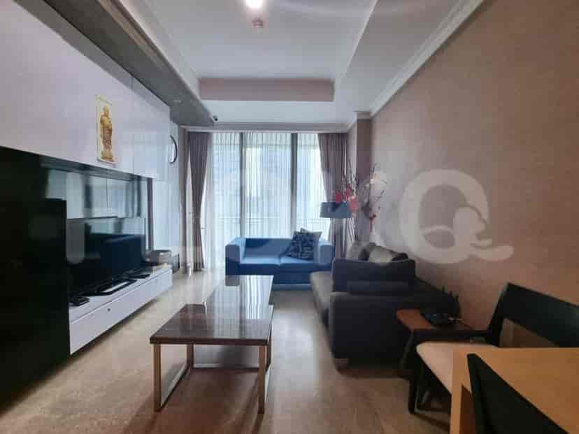 Modern living room with a blue sofa, wall-mounted TV, and city view through a large window.
