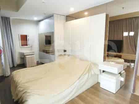 A modern bedroom with a king-sized bed and mirrored accents.
