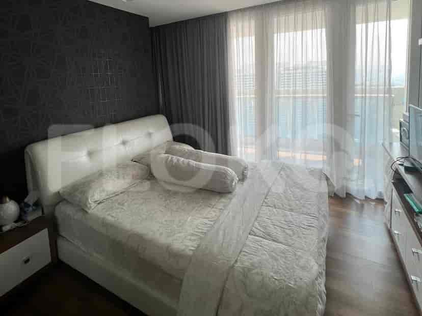 Kamar tidur modern dengan tempat tidur kulit putih dan jendela besar.