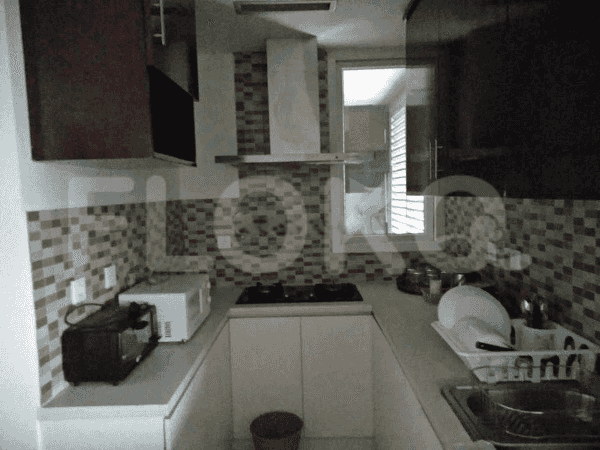 Dapur ringkas dengan lemari kayu gelap, backsplash ubin mozaik, dan peralatan stainless steel.
