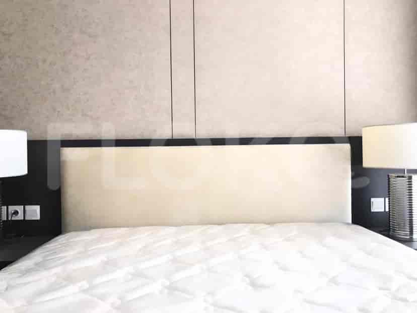 A bedroom featuring a bed with a beige headboard and two bedside lamps.