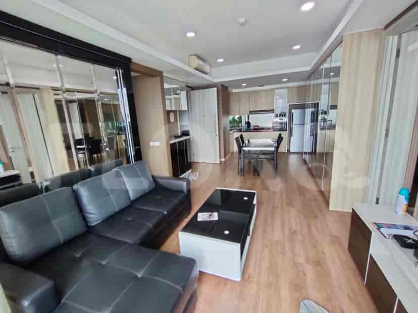 Modern living area with black leather sectional, mirrored walls, and a view into the kitchen.