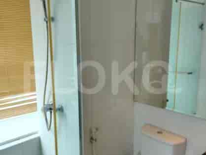 Kamar mandi yang terang dengan shower, penutup kaca, dan perlengkapan modern.