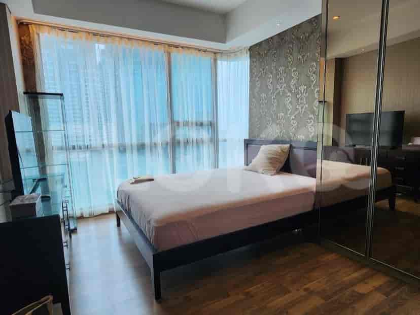 A well-lit bedroom with a bed, large windows, and a mirror.