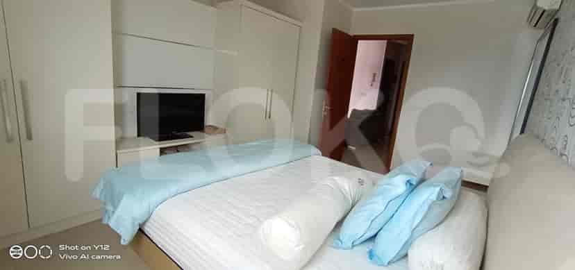 A well-lit bedroom with a bed, wardrobe, and a mounted TV.