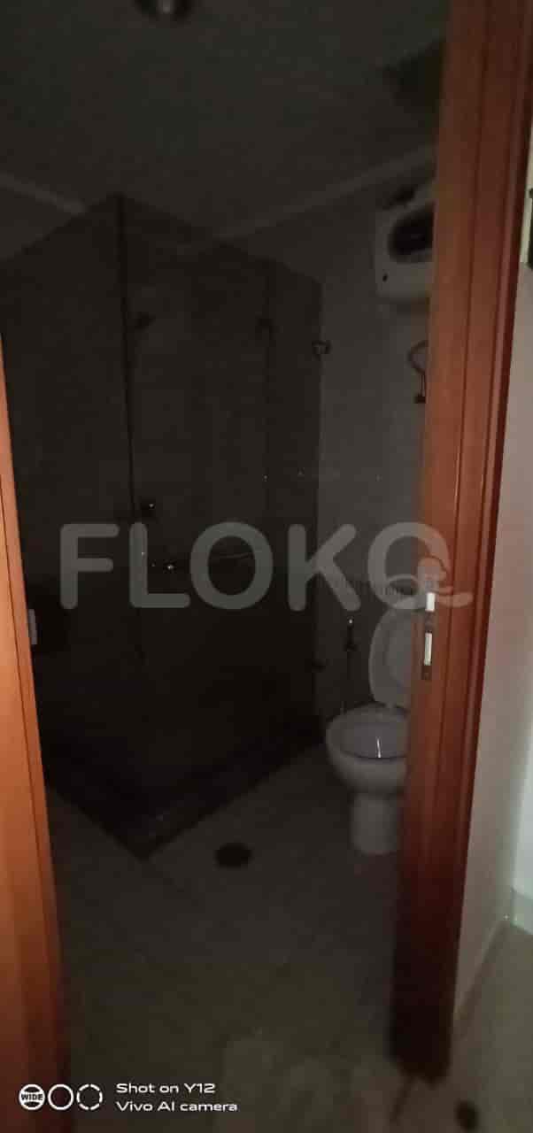A view of a toilet and a glass-enclosed shower inside a bathroom.