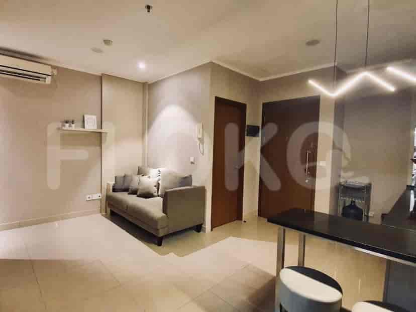 Ruang tamu modern yang menampilkan sofa, meja samping, dan akses ke dapur dan ruangan lain.