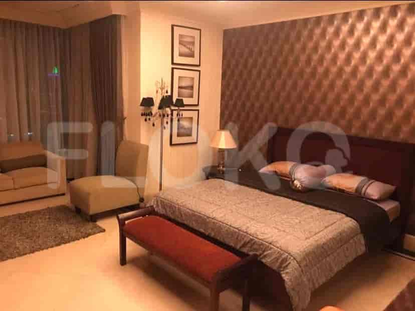 A bedroom with a large bed, seating area, and decorative elements.