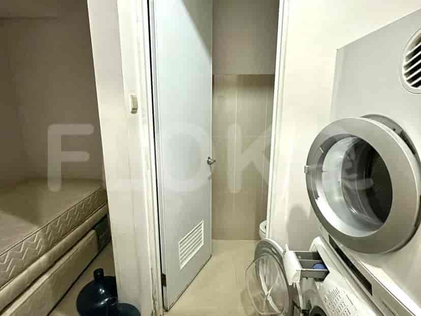 A laundry room with a washing machine, a dryer, and a small bed.