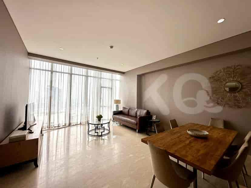 A modern living and dining area with a brown leather sofa, glass coffee table, and a wooden dining table with chairs, large windows.