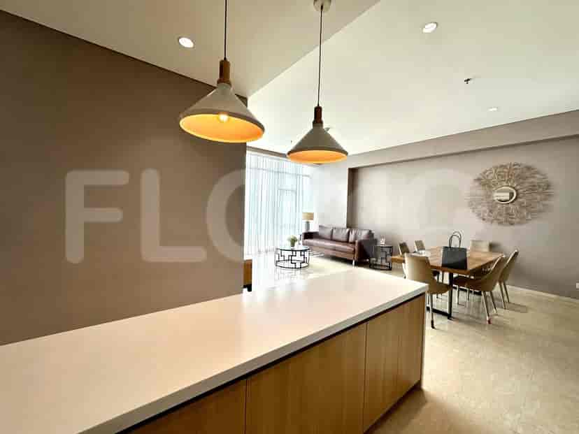 A modern living and dining area with pendant lights, a brown leather sofa, a dining table with chairs, and large windows.