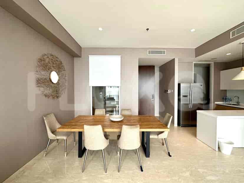 A dining area with a wooden dining table and beige chairs, adjacent to a modern kitchen.
