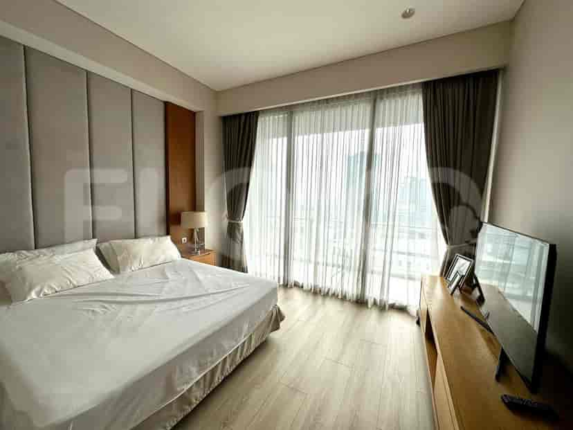 A bedroom with a bed, bedside tables, and a large window.