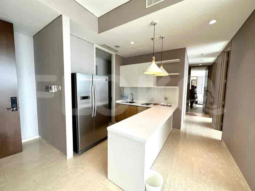 A modern kitchen with white cabinets, a stainless steel refrigerator, and pendant lights.