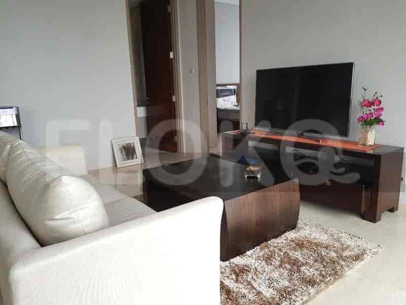 Living room featuring a white sofa, a TV on a wooden stand, and a coffee table with a rug.